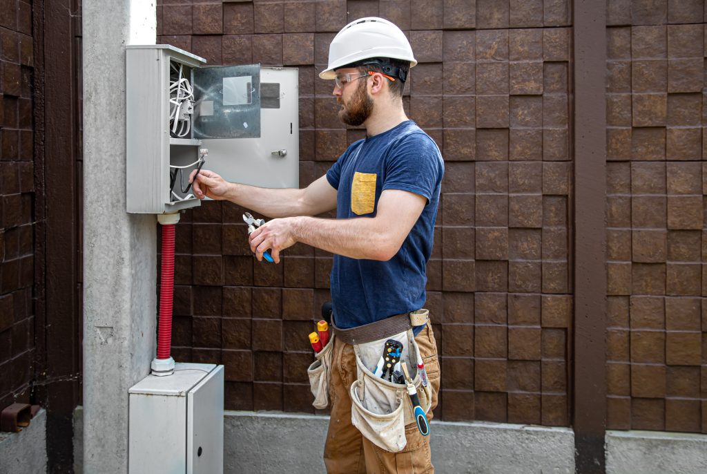 JaySparks Electrical Electrical Services Peakhurst NSW, Sydney Electrician Builder Examines The Cable Connection In The Electrical Line In Switchboard.