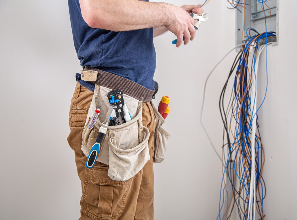JaySparks Electrical Electrical Services Peakhurst NSW, Sydney Electrician Builder Examines The Cable Connection In The Electrical Line In Switchboard Indoor.