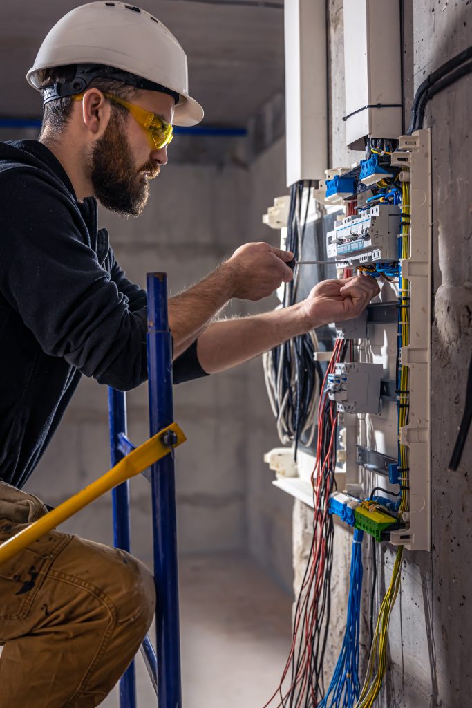 JaySparks Electrical Electrical Services Peakhurst NSW, Sydney A Male Electrician Works In A Switchboard With An Electrical Connecting Cable.