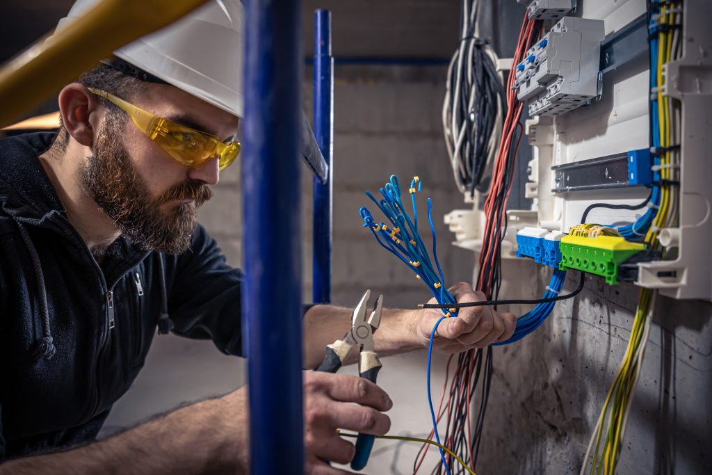 JaySparks Electrical Electrical Services Peakhurst NSW, Sydney A Male Electrician Works In A Switchboard With An Electrical Connecting Cable.